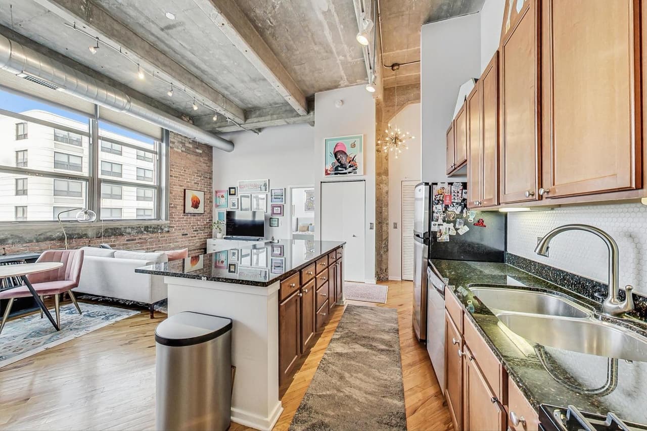 Kitchen with island seating, living area and tall windows beyond