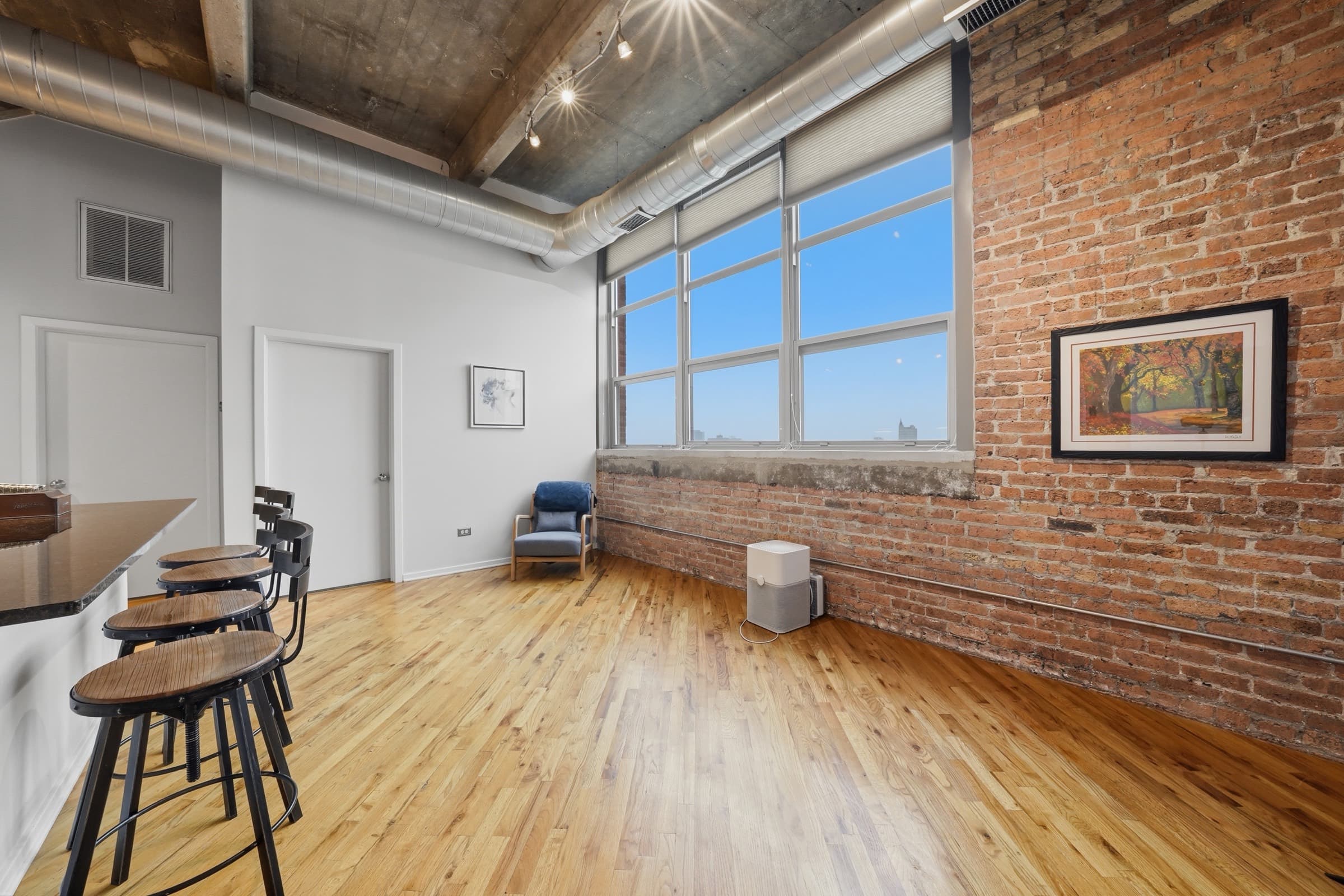 Living area with exposed brick and a tall factory window