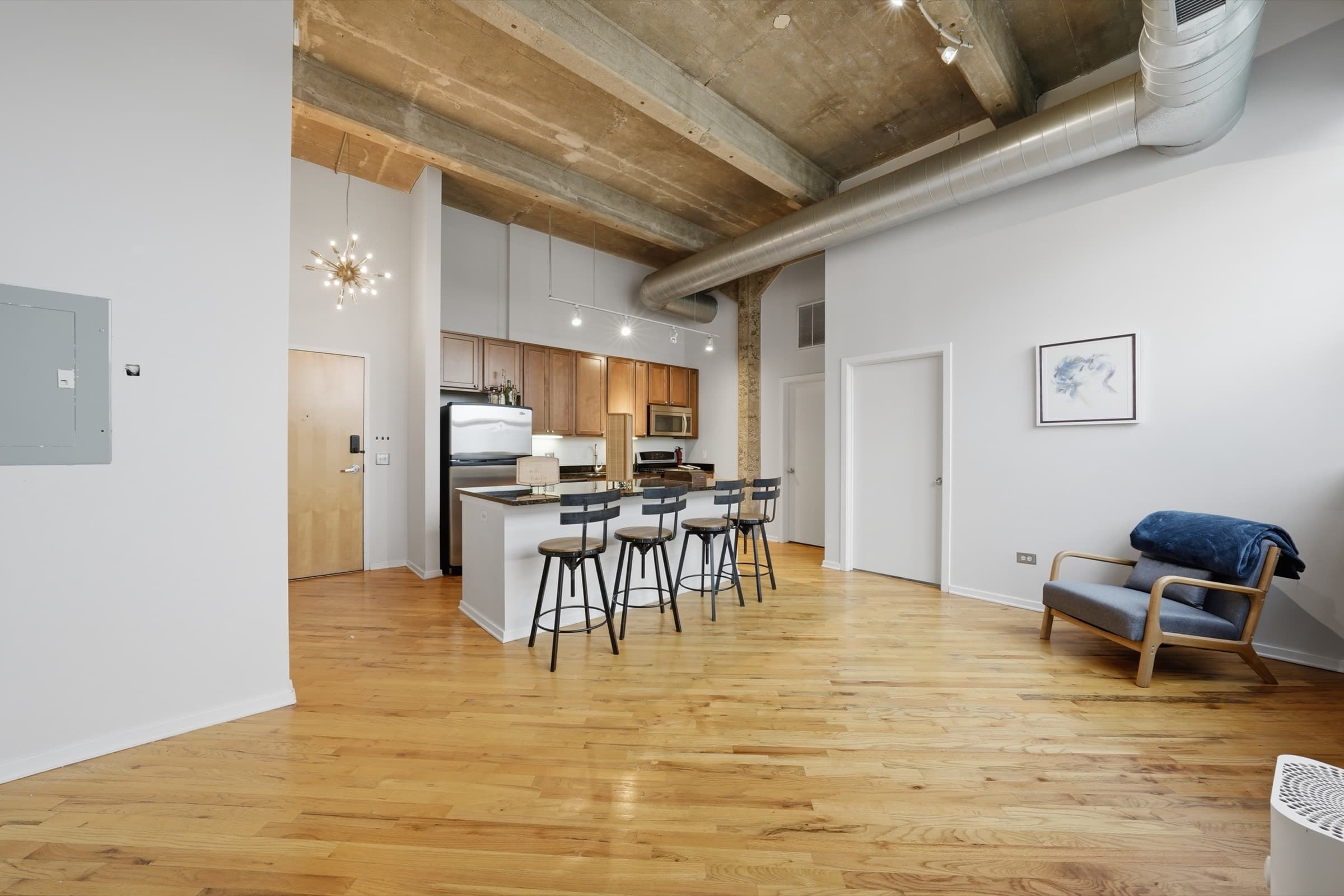 The main room looking toward the kitchen, with concrete ceilings and hardwood floors