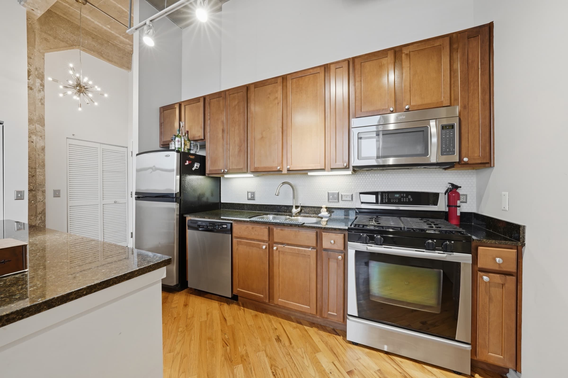 Kitchen run with gas range, microwave, dishwasher and granite counters
