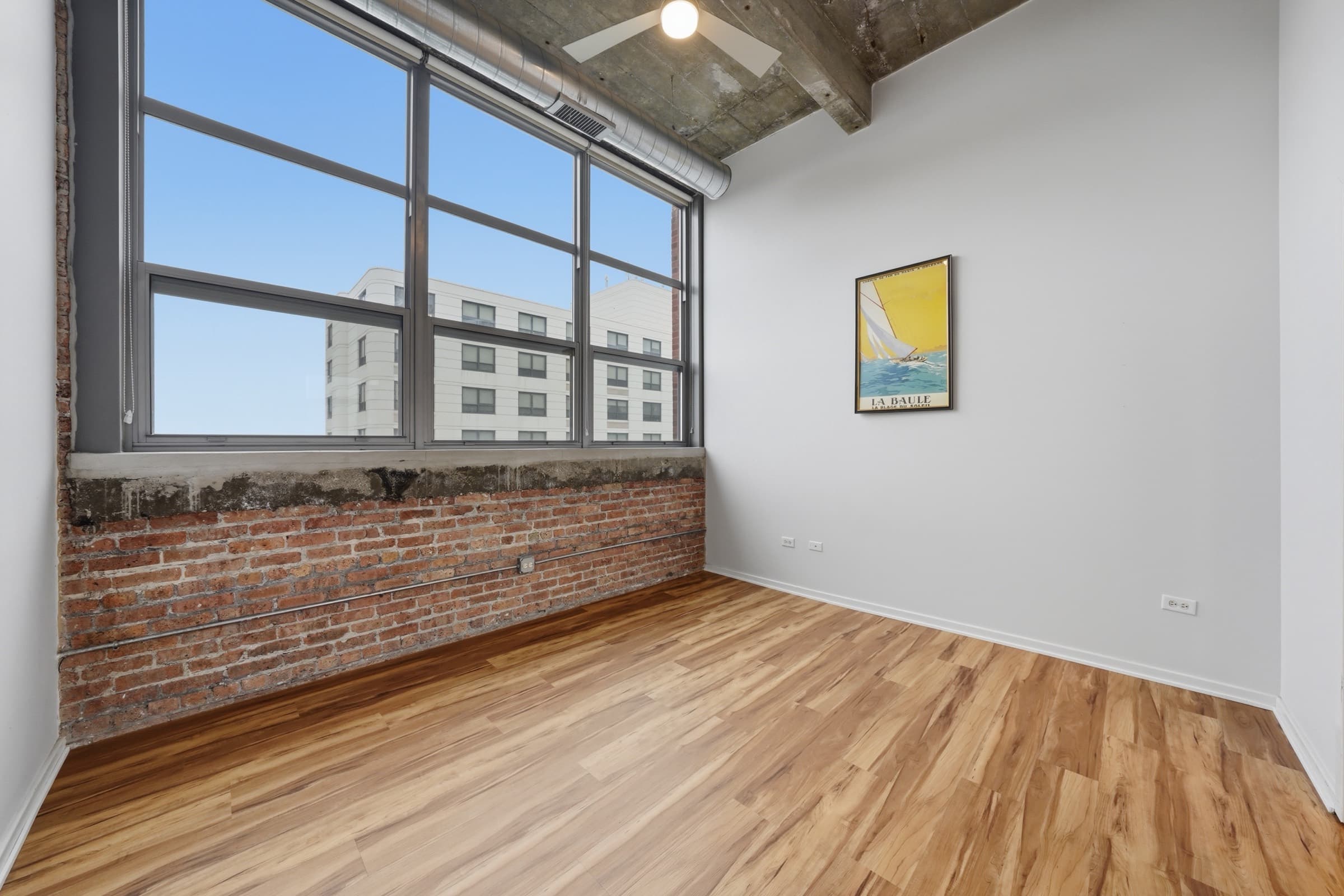 Primary bedroom with exposed brick and a wide factory window