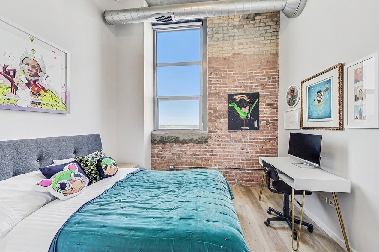 Bedroom two with desk corner, brick wall, and tall window